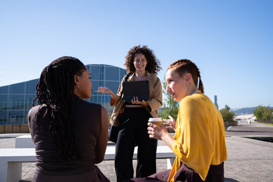 African American and white women having outdoor meeting with tablet