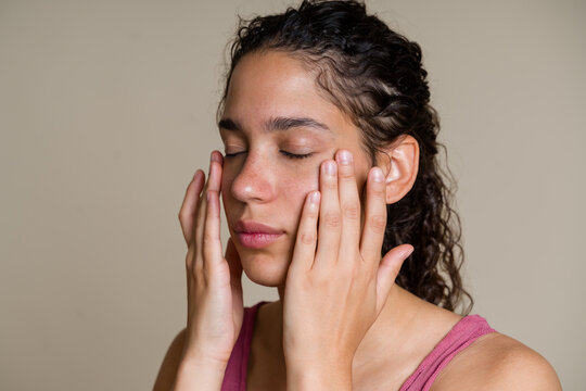 Hispanic woman applying moisturizer to her face in skincare routine