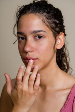 Hispanic woman touching lips in close-up studio portrait in a studio