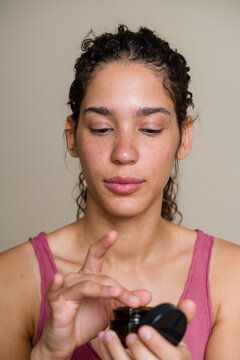 Hispanic woman applying cream from jar in a beauty shoot