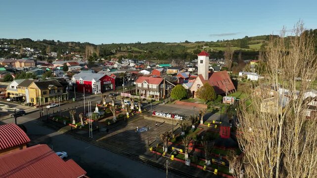 A slow aerial pullback reveals the heart of Curaco de V&eacute;lez, its white church tower and colorful buildings framed by bare autumn poplars overlooking the quiet Chilo&eacute; countryside.