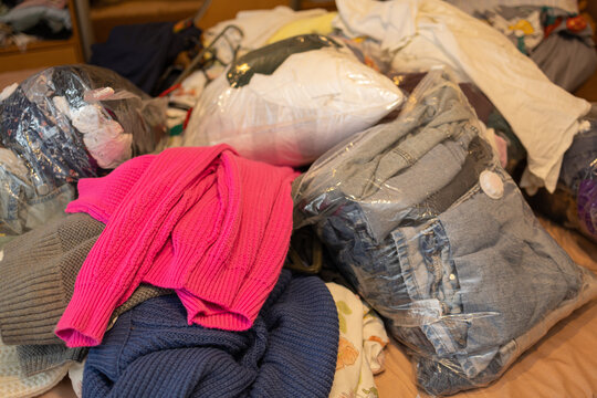 Clothing and Household Textiles Prepared for Moving to a New Home. Different clothes and household textiles gathered and sorted during preparation for a residential move. The collection includes folde