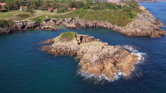 Scenic drone orbit shot of small offshore island and rugged Asturian coastline 