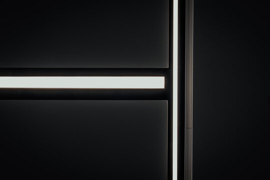 minimal black architectural interior with glowing horizontal and vertical led light strips, geometric lines, dark surfaces, and dramatic modern lighting composition