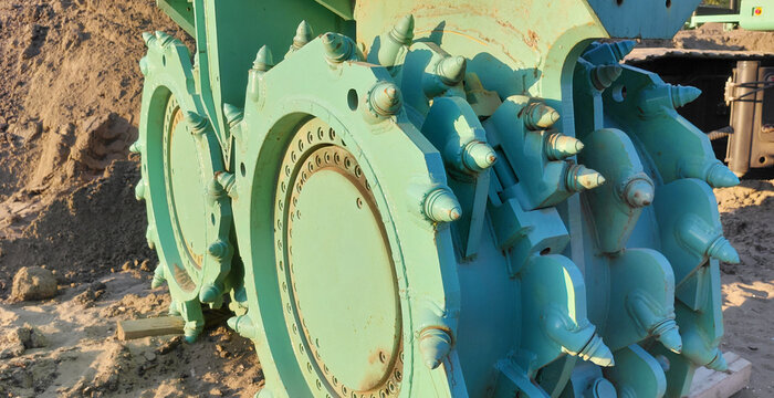 Close up view of a road milling machine drum, showing the heavy duty cutting teeth used for asphalt and concrete removal