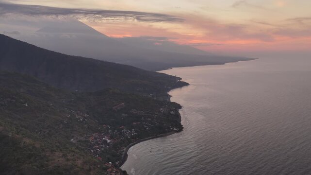 Aerial view of amed coastline with mount agung volcano at sunset