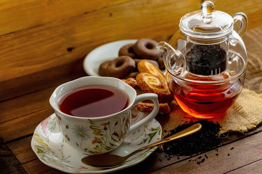 T&egrave; nero con teiera di vetro , tazza con piattino e pasticcini