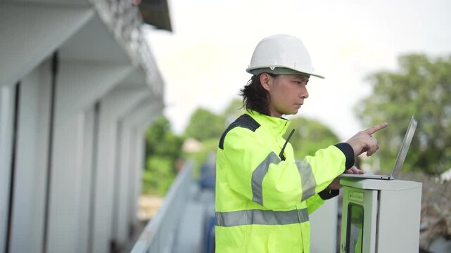 Engineer checks outdoor electrical control cabinet while holding walkie talkie during inspection of water gate monitoring and control equipment.