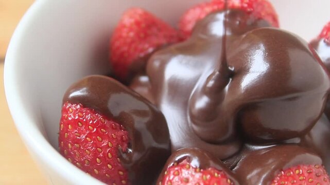 pouring melted chocolate over a strawberry