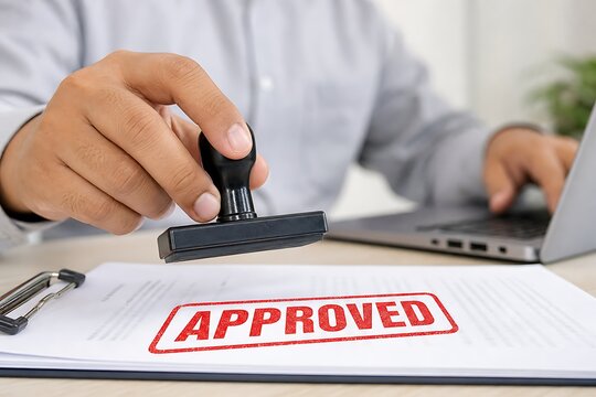 Business person stamping approved on contract document with red ink stamp at office desk