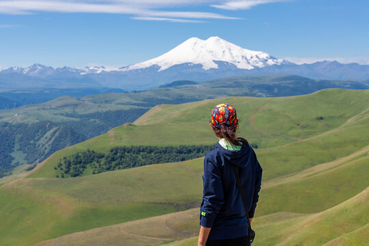 A rear view of a slender, athletic woman admiring the beautiful mountain scenery