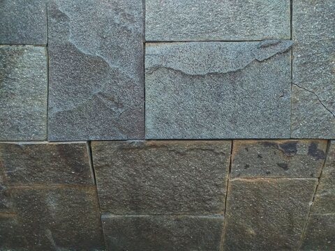 Grey textured stone block pattern on an architectural facade. Ideal for architectural design projects, background textures, and construction themed graphics.