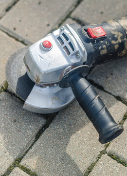 Angle Grinder Lying on Pavement, Used Power Tool Close-Up Outdoors