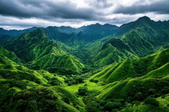 Lush green mountains with sharp ridges and deep valleys under a moody overcast sky in a cinematic landscape shot for travel and nature branding