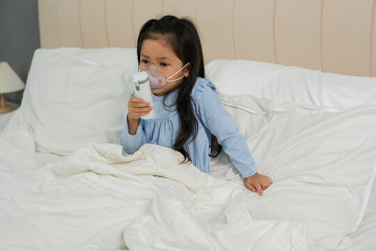 sick preschool child girl using respiratory nebulizer mask in bed