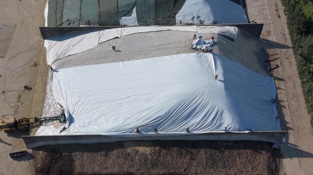 Drone view of large covered silage storage pits at an Italian livestock farm. The organized agricultural infrastructure provides useful context for farming operations. 