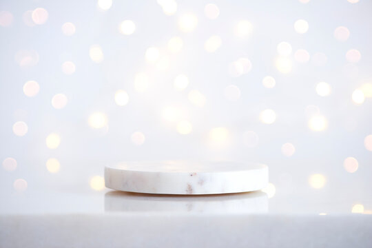 Minimalist Christmas background with white stone podium and bokeh lights
