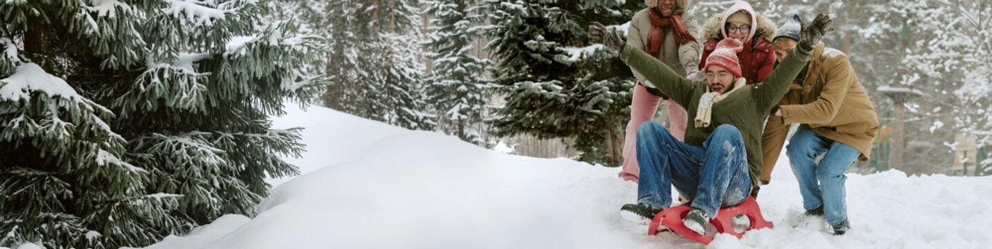 Header of multiethnic group of young adults sledding down snowy hill in winter park. Perfect for winter vacation advertising, seasonal friendship campaigns, and outdoor leisure promotion