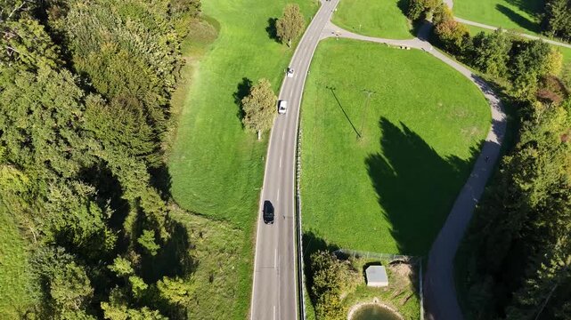 Traffic Approaching on German Country Road. Cinematic forward drone flight moving towards oncoming traffic and a semi-truck on a regional highway through green rural landscapes in southern Germany.