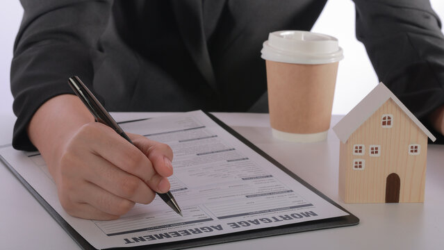 Focused professional signing mortgage agreement contract during housing finance loan application process at an office desk