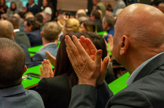 People clapping hands and applauding at a conference or public event.
