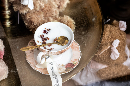 Decorative teacup candle with botanical elements gold spoon and ribbon surrounded by soft toy bears