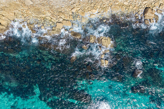 Aerial downward view of clear turquoise water meeting the rocky shoreline at Trial Bay near South West Rocks, New South Wales, Australia. 