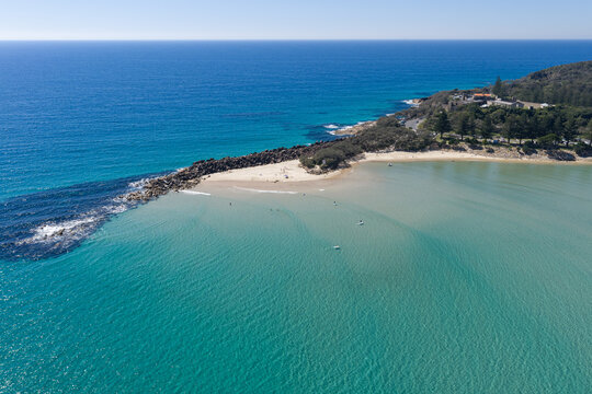 An aerial view of Laggers Point surrounded by clear turquoise ocean, with the historic Trial Bay Gaol visible in the background. 