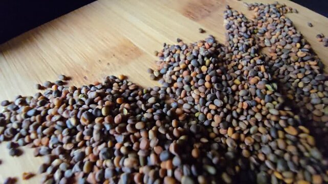 Creative arrangement of organic arugula seeds spread across a textured wooden background, showcasing natural patterns and rich details for gardening and agriculture concepts.   