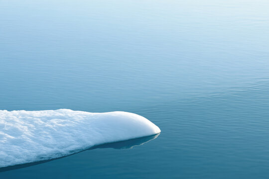 White sea ice shelf extending across calm blue ocean water creates serene minimalist scene with soft texture, gentle reflection, and spacious natural background for design