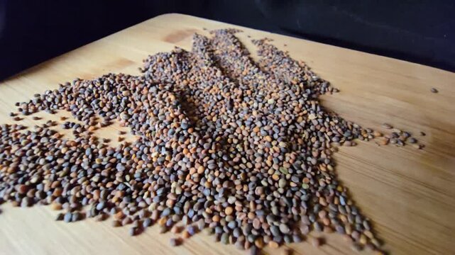 Creative arrangement of organic arugula seeds spread across a textured wooden background, showcasing natural patterns and rich details for gardening and agriculture concepts.   