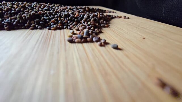 Close-up of organic arugula seeds scattered across a wooden board, highlighting fine agricultural details and natural shapes for gardening and healthy food themes.   