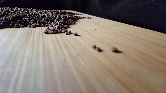 Close-up of organic arugula seeds scattered across a wooden board, highlighting fine agricultural details and natural shapes for gardening and healthy food themes.   