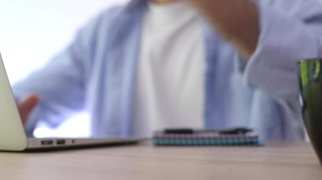 Frustrated man clenching his fist after receiving bad news or facing a computer problem, showing anger and irritation while typing on his laptop in the office workplace