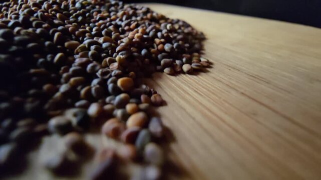 Macro shot focusing on scattered organic arugula and rocket seeds on a wooden table, highlighting natural textures and agricultural details.   