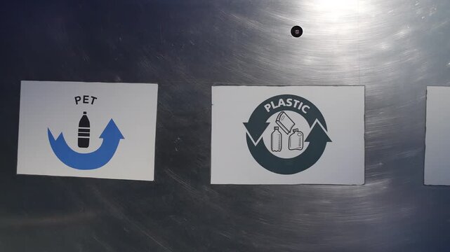 Pan right across PET plastic and metal labels on a waste sorting bin
