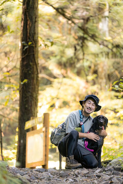 [晩夏～秋イメージ]愛犬と登山を楽しむ日本人男性、犬とのハイキング、アウトドア、トレッキング、自然の中を一緒に旅するペットとの休日