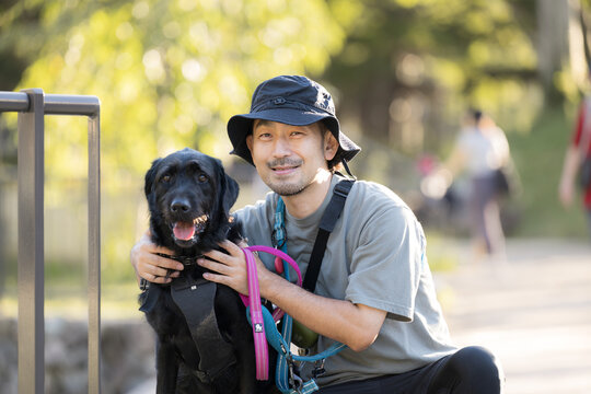 [晩夏～秋イメージ]大型犬と顔を寄せてカメラ目線で笑顔の日本人男性、犬と飼い主の絆、信頼やコミュニケーションイメージ
