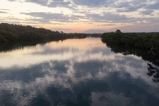 Aerial view along Back Creek at South West Rocks, New South Wales, during sunset, with calm water reflecting the colourful evening sky and surrounding mangrove landscape.