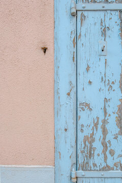 Light Blue Wooden Shutter with Peeling Paint, Vintage Door Detail, Metal Hinges, Rustic Pastel Pink Wall Background