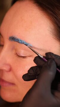 Woman receiving blue thread eyebrow threading close up