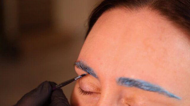 Woman receiving blue eyebrow microblading treatment close up with
