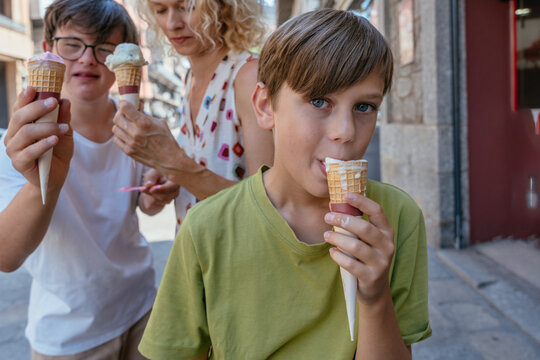 Curious young boy eating gelato while family enjoys summer treat on Spanish street
