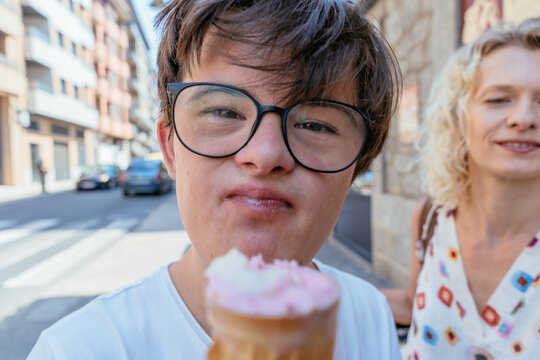 Closeup portrait of teenage boy with Down syndrome enjoying gelato in small provincial town