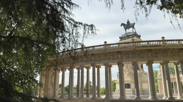 Impressive colonnade and equestrian statue of the Monument to Alfonso XII in the Buen Retiro Park, a major tourist attraction and landmark in Madrid, Spain, surrounded by green trees