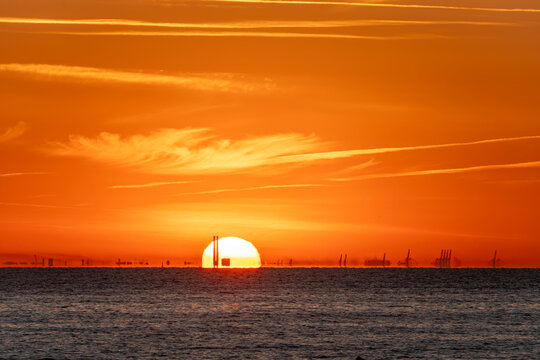 Luc-Sur-Mer, France - 08 08 2022:  Colorful sunrise over the sea and port of Le Havre far away