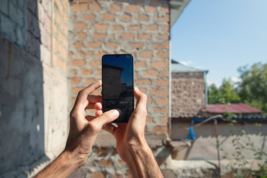 Man taking picture house wall.