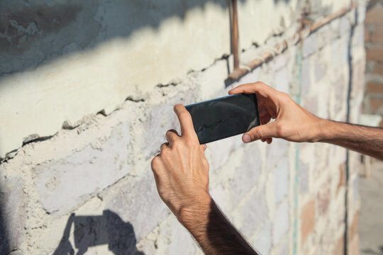 Man taking picture with a mobile phone cracked wall after earthquake.