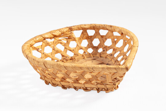 Woven wicker basket with hexagonal pattern and natural tan color, empty and isolated on white background for product display or decor