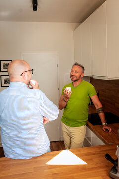 Gay couple talking and having coffee in the kitchen